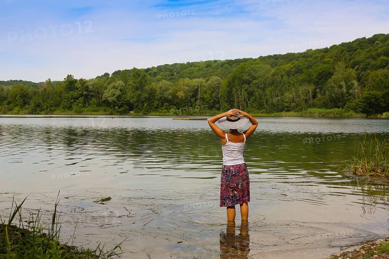 Woman with sun hat and skirt standing in the water