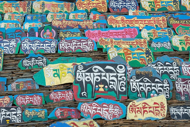 Huge piled up mountain of mani stones with Tibetan writing at a Tibetan monastery in the grasslands of Tagong