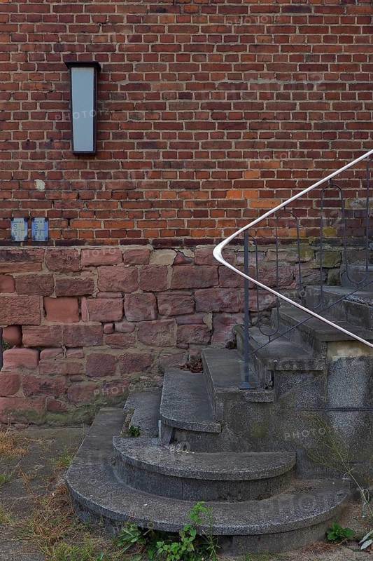 Stairs with railing in front of red brick wall