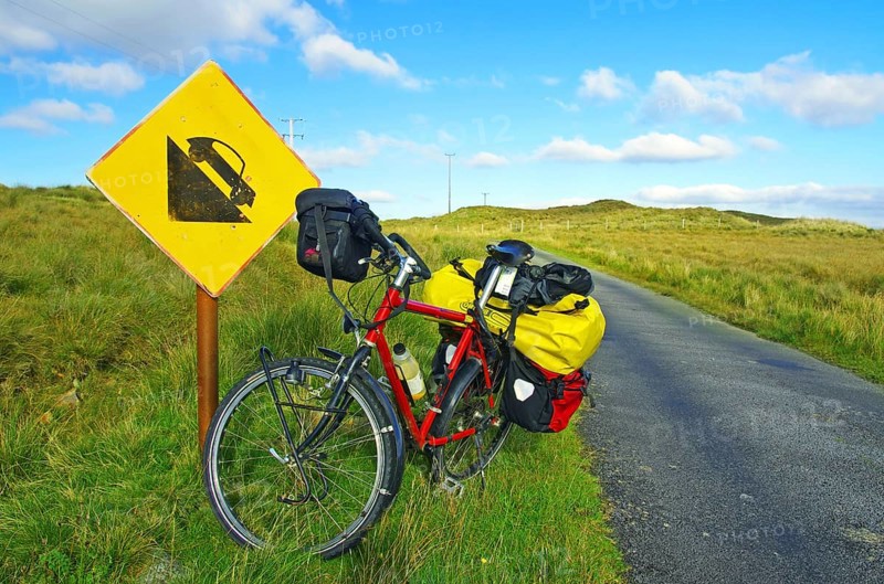 Bicycle in front of road sign warning of steep gradient