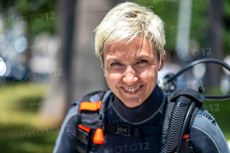 Portrait of a happy scuba diver with an oxygen tank and wet suit already on