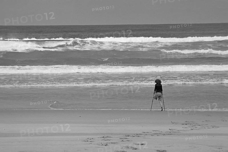 One-legged young woman on crutches by the sea