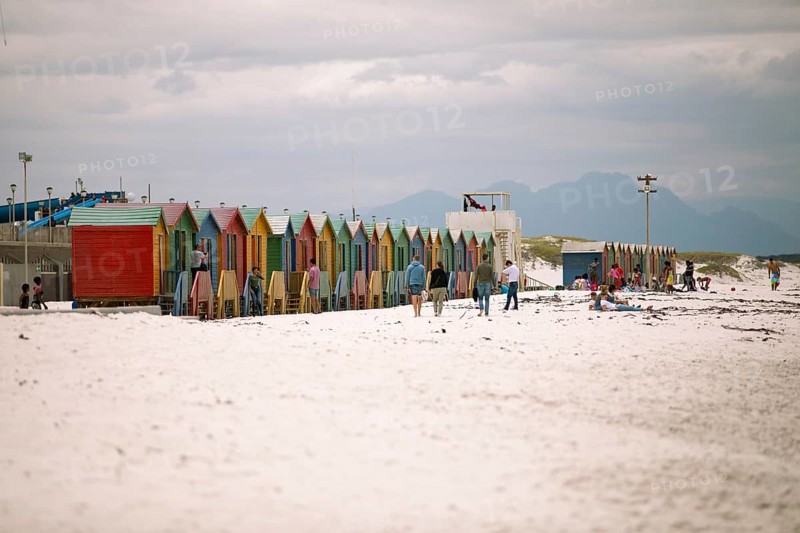 Holidaymakers in front of colourful beach huts