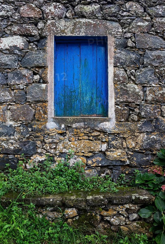 Residential house with stone facade and blue closed window in Rocha da Relva