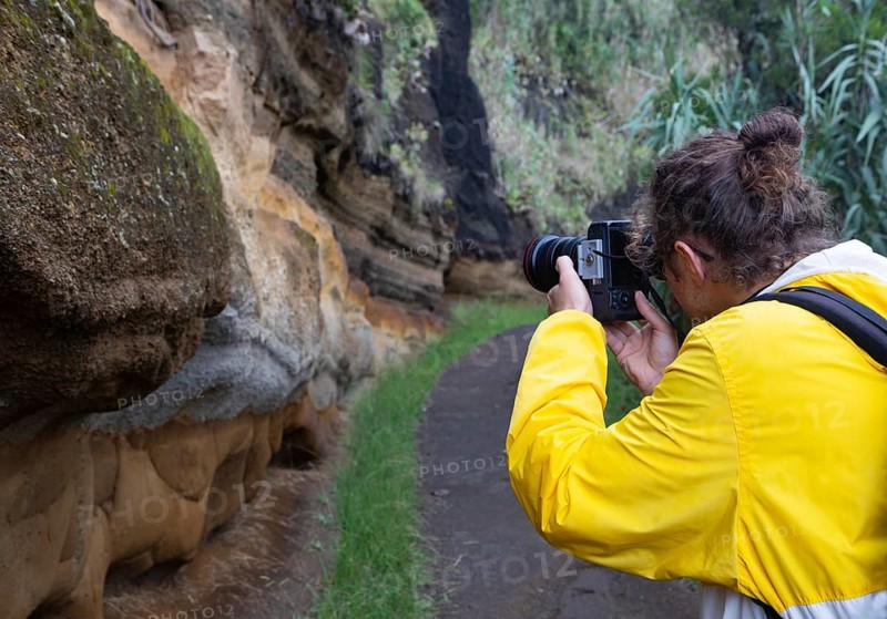 Hiker photographs eroded sand and lava rock on the path to Rocha da Relva