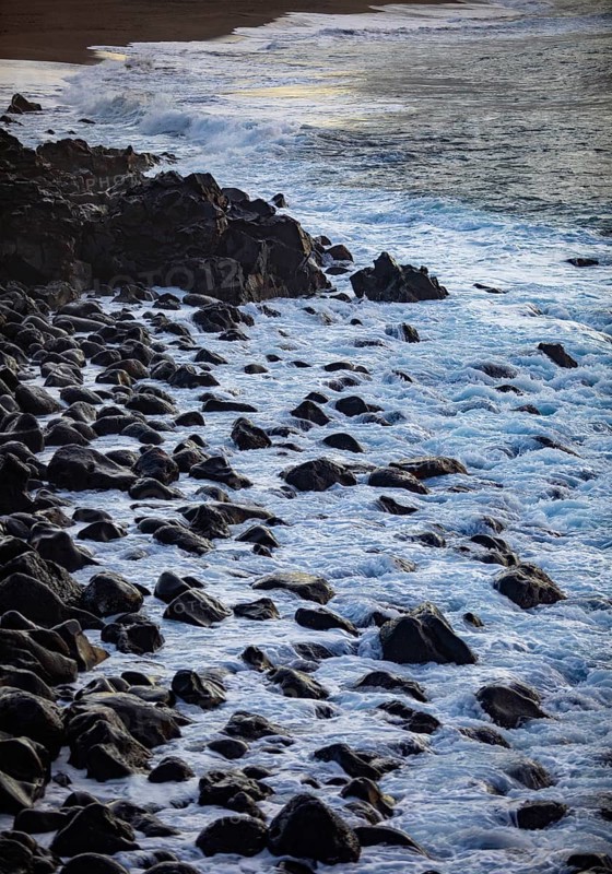 Large black lava stones in the surf on the beach of Praia de Santa Barbara