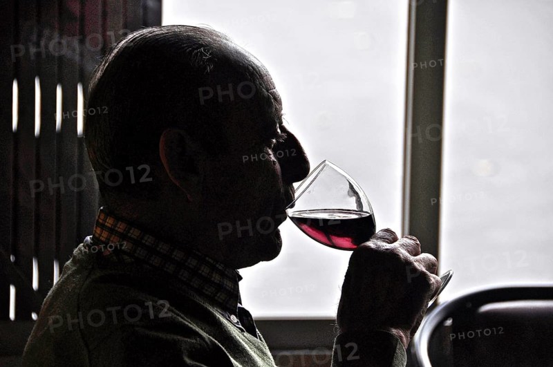 Old man drinking red wine against the light