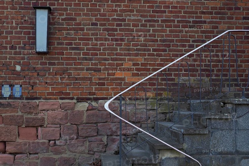 Stairs with railing in front of red brick wall