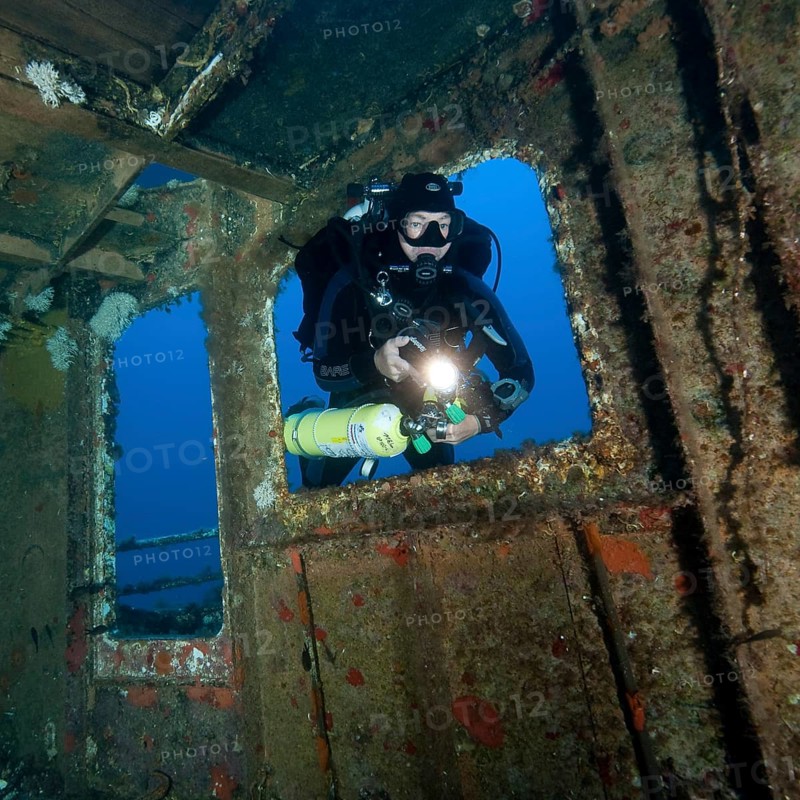 Diver views interior of shipwreck has special equipment for mixed gas diving