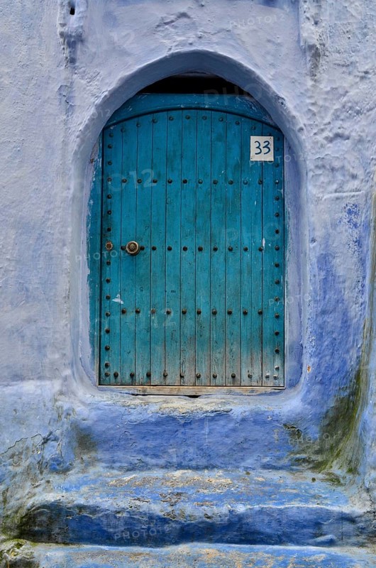 Mint-coloured entrance door with blue wall and house number 33