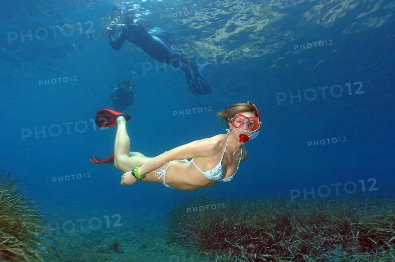 Snorkeler dives down swims over sea grass