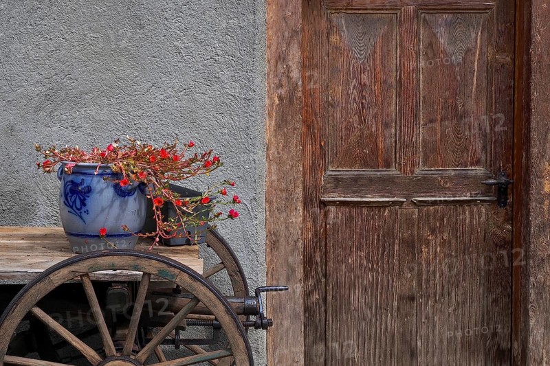 Still life with clay pot and wooden wagon in front of wooden door