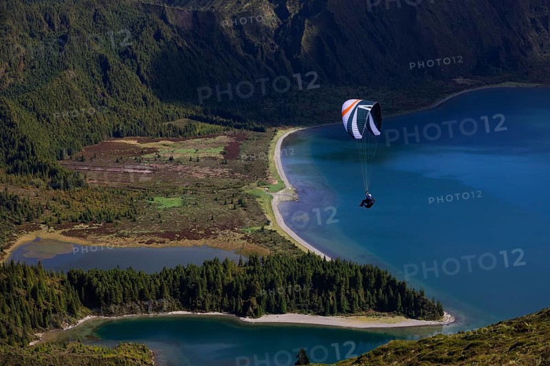 paraglider in flight over the crater lake Lagoa do Fogo