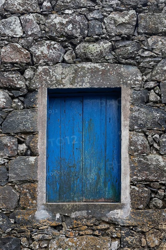 Residential house with stone facade and blue closed window in Rocha da Relva