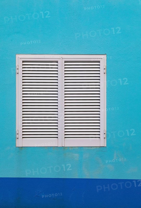 Light blue house facade with closed white shutters