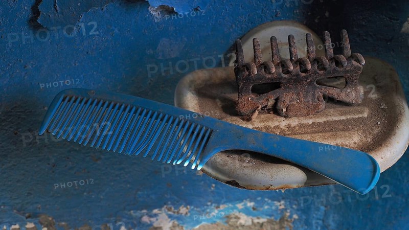 Old comb with hairclip in soap dish in front of blue wall