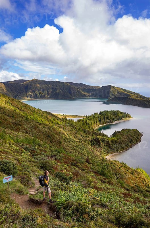 Hiker at the crater rim with view to the crater lake Lagoa do Fogo