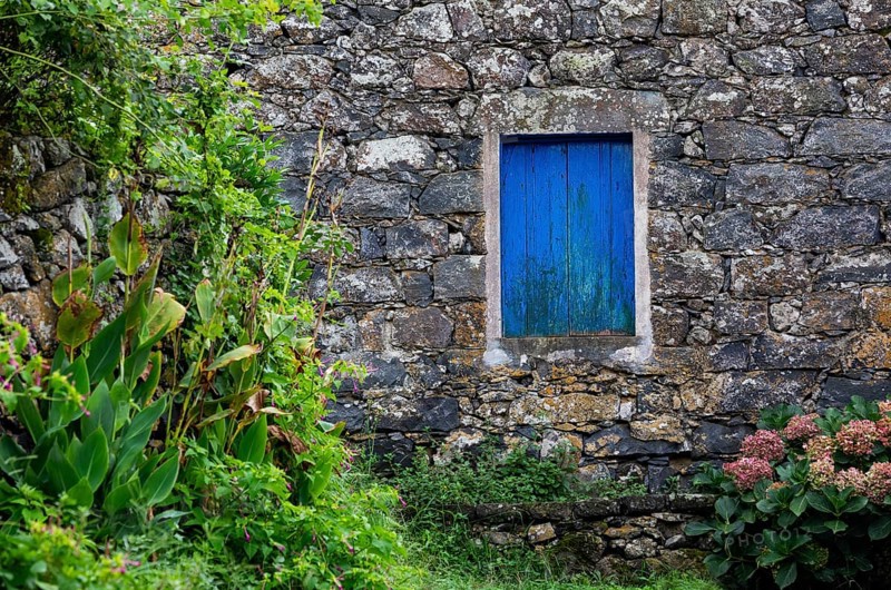 Residential house with stone facade and blue closed window in Rocha da Relva