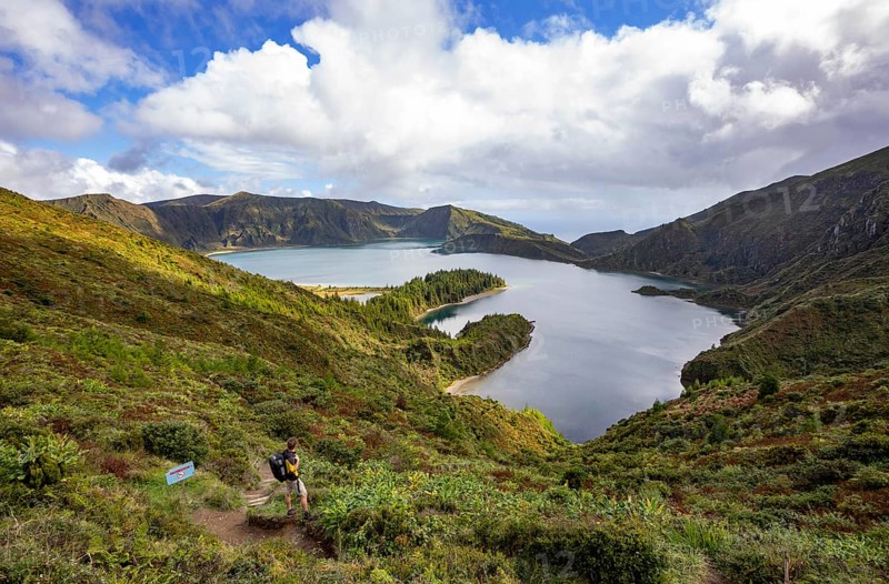 Hiker at the crater rim with view to the crater lake Lagoa do Fogo
