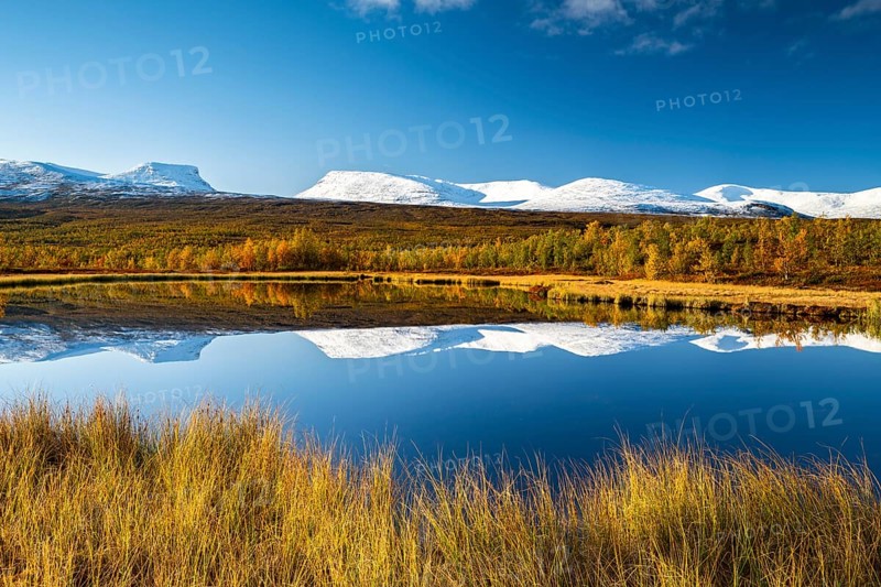 Mountain group Lapporten and snowy mountains of Abisko National Park reflected in small pond