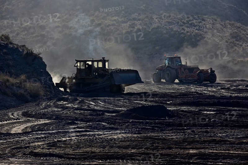 Bulldozers pushing hilly earth flat