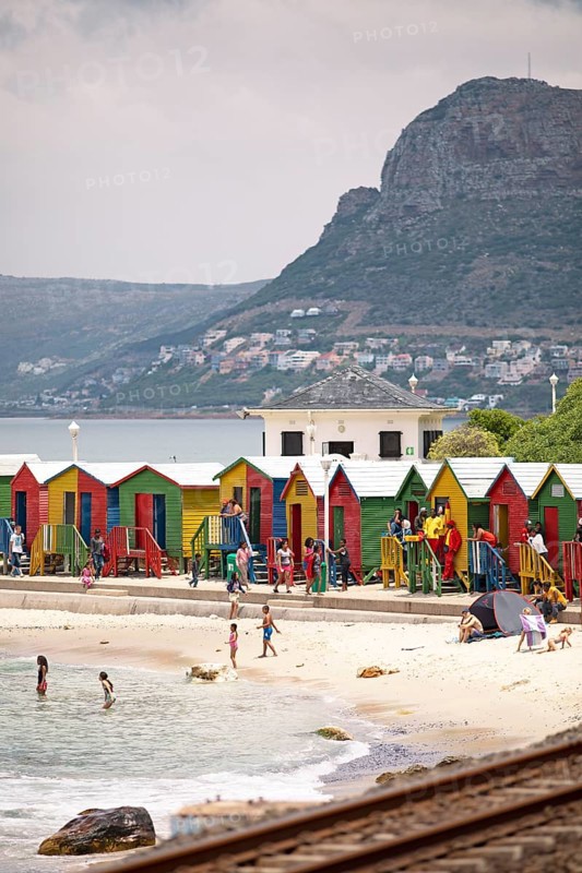 Holidaymakers in front of colourful beach huts
