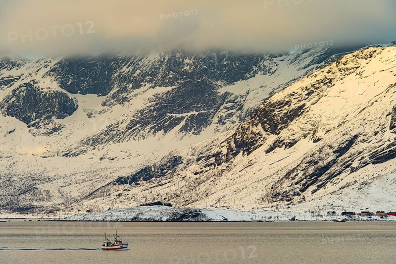 Fishing boat in winter Scandinavian landscape at the fjord