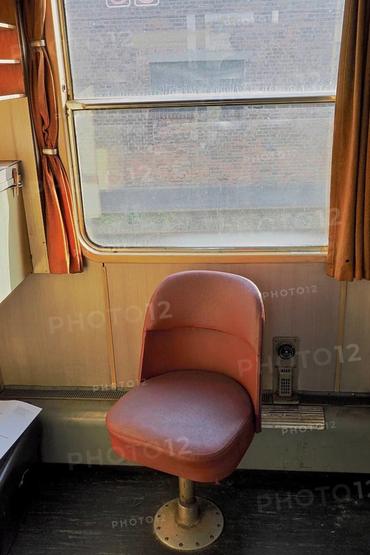 Red single seat inside an old train compartment