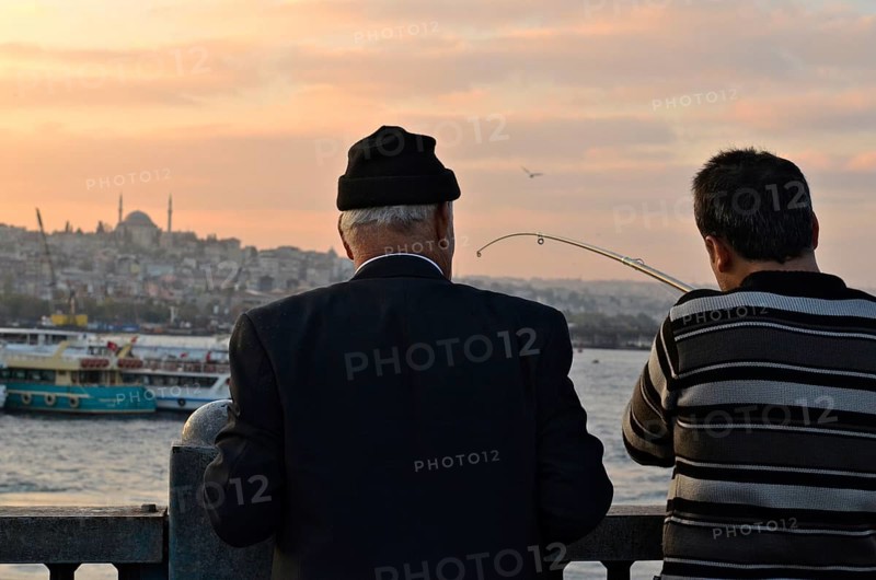 Anglers on Galata Bridge with a view of the Sueleymaniye Mosque at sunset