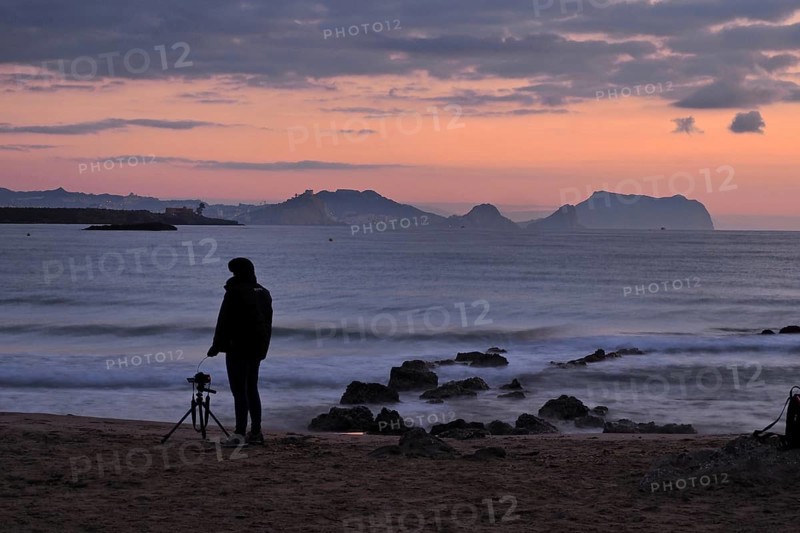 Photographer with camera and tripod in the morning at the sea