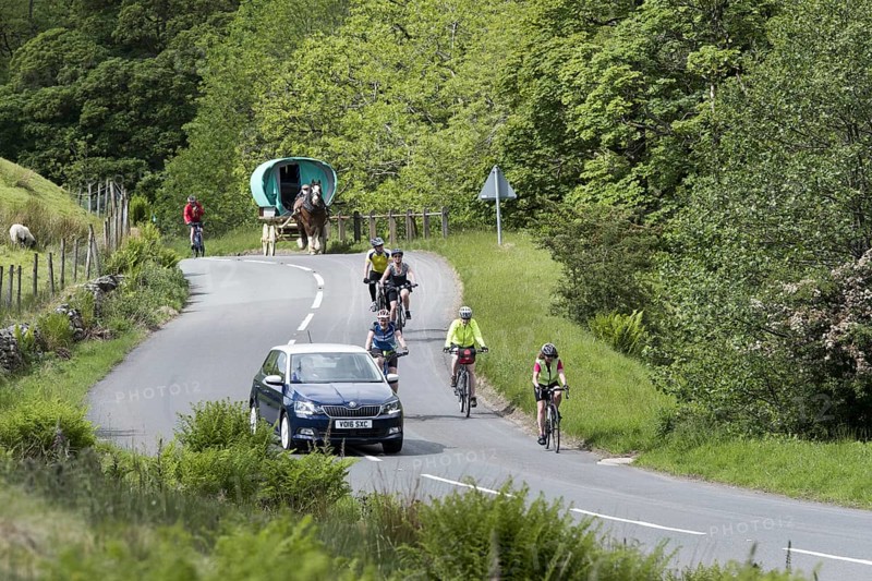 Vehicles overtaking on a busy rural road in Cumbria