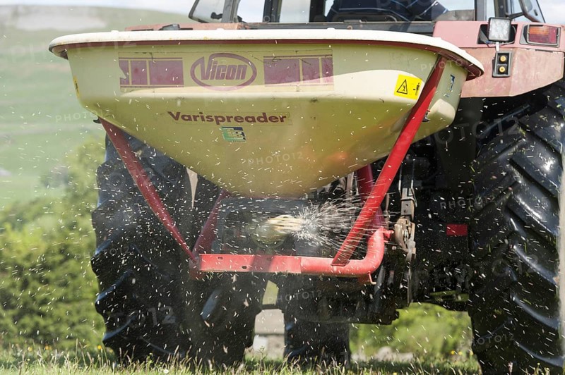 Speading fertiliser on a traditional Dales meadow with a Case International tractor. Hawes