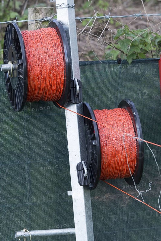 Electric fence wire on rolls around the edge of a field