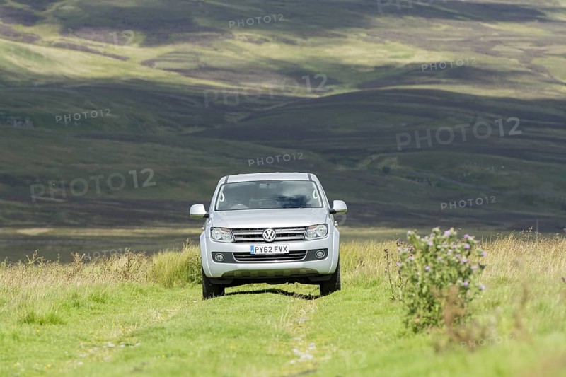 Four wheel drive VW Amarok twin cab pick up driving across upland pasture in North Yorkshire