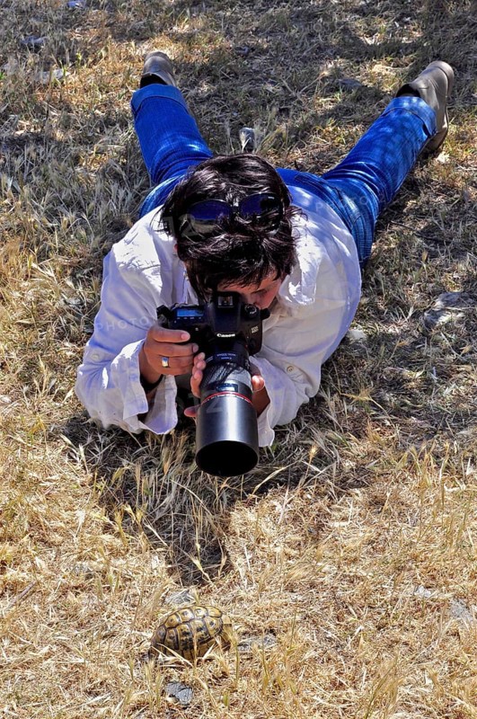 Photographer lying on her stomach with telephoto
