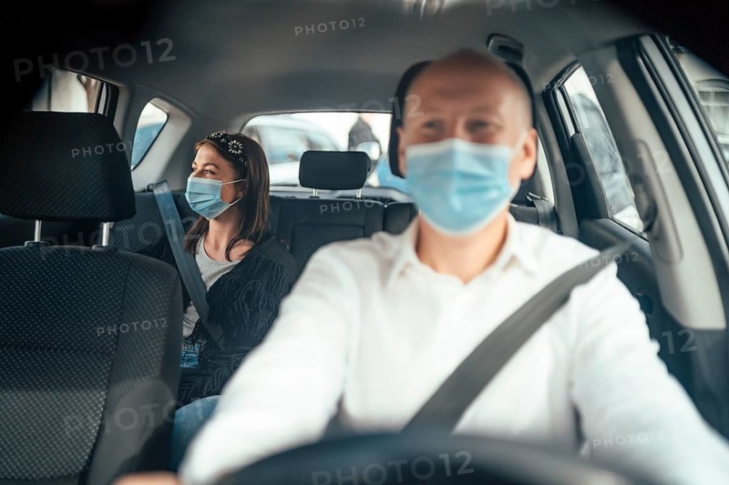 Taxi driver in a mask with a female client on the back seat wearing mask