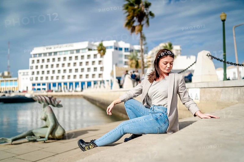 Young woman sitting by the marina in Faro