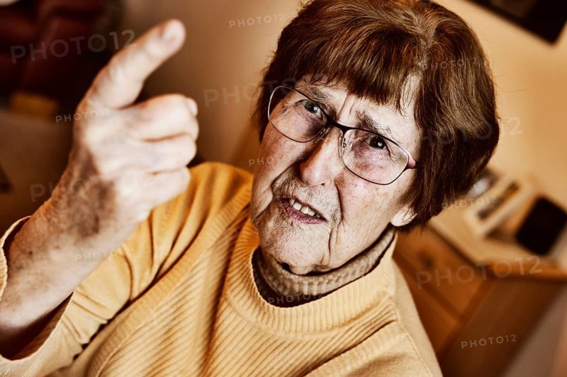 Angry senior citizen threatens with her raised index finger