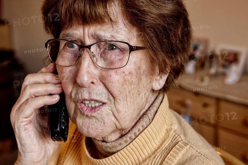 Senior citizen at home while phoning looks uncertain