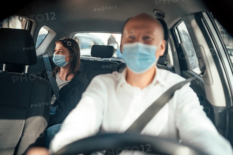 Taxi driver in a mask with a female client on the back seat wearing mask