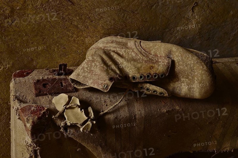 Work shoe lies on old canvas suitcase
