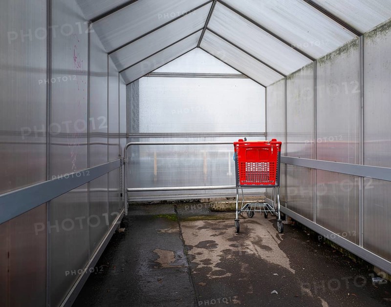 Last red shopping trolley under a plastic roof