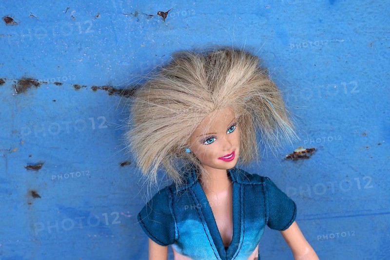 Barbie doll leaning against blue metal plate