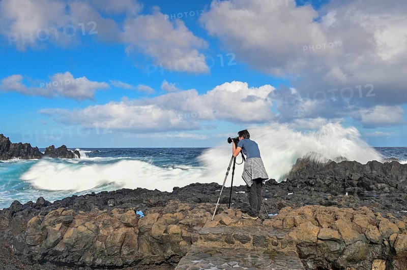 Photographer taking pictures in strong waves at the sea