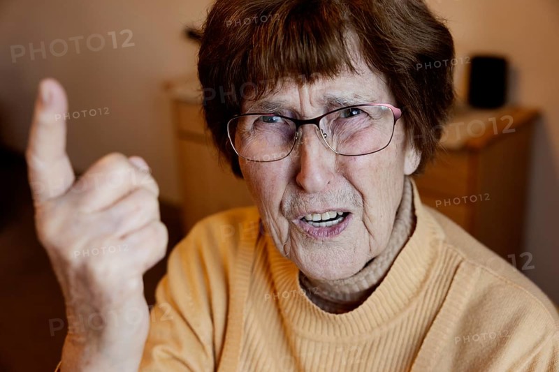 Angry senior citizen threatens with her raised index finger
