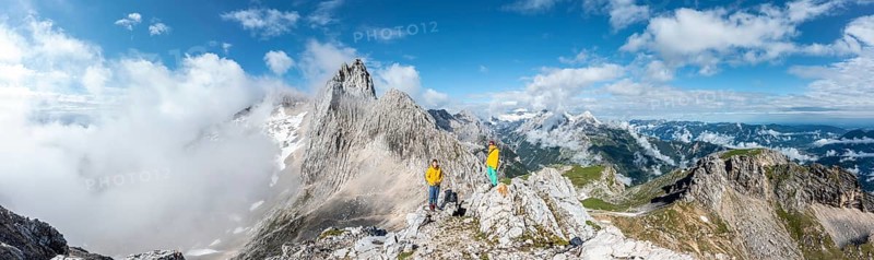 Two hikers in front of alpine panorama