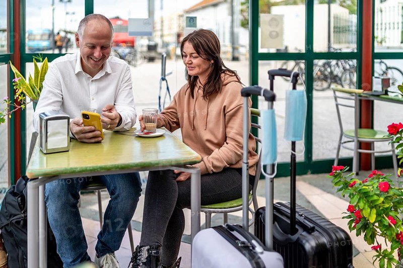 A couple of travelers drinking coffee and checking something on the phone
