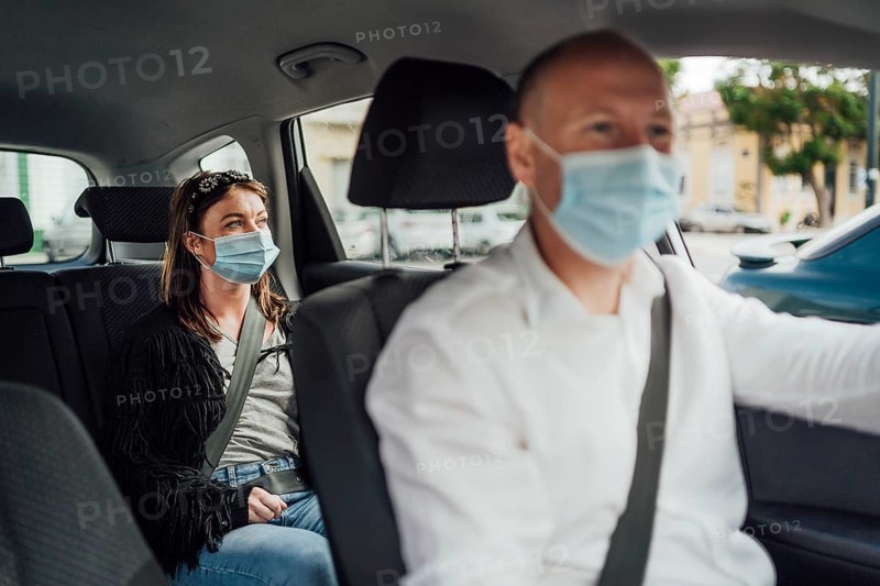 Taxi driver in a mask with a female client on the back seat wearing mask