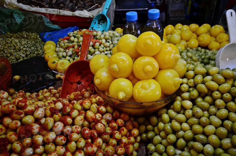 Bowl of Moroccan salted lemons on mountain with varieties of olives