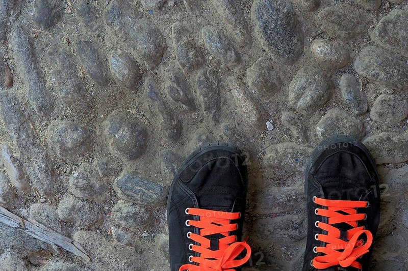 Black sports shoes with red shoe laces on street